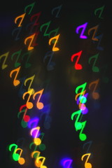 colorful bokeh on a dark background in the form of musical notes