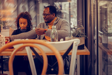 Father wearing orange polo neck having breakfast with daughter