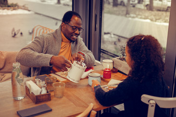 Curly daughter asking for more tea while having breakfast with father