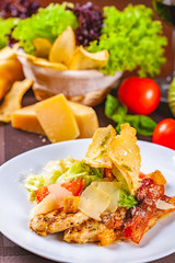 Caesar salad with bacon and chicken on white plate