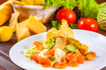 Caesar salad with salmon on white plate