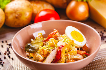 Potato salad with chicken and bacon in beige bowl