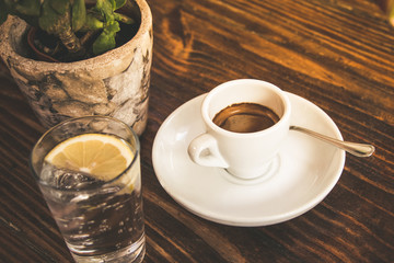 Closeup of a cup of coffee on a wooden table in the morning with sunlight and relaxing in the free time. Photo of a moment of relax in the holiday with a hot beverage enjoying the breakfast 
