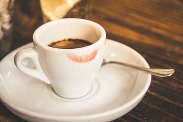 Closeup of a cup of coffee on a wooden table in the morning with sunlight and relaxing in the free time. Photo of a moment of relax in the holiday with a hot beverage enjoying the breakfast.