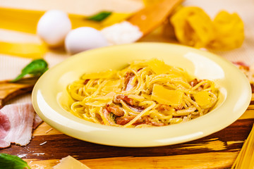 Spaghetti carbonara with bacon and parmesan cheese in beige plate