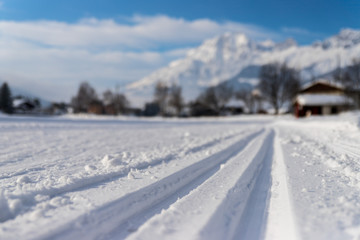 Fototapeta na wymiar Cross-country skiing in Austria: Slope, fresh white powder snow and mountains, blurry background