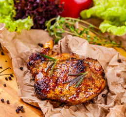 Grilled pork chop with spices and herbs on parchment paper