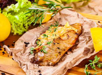 Baked seabass fillet with herbs and spices on wooden board