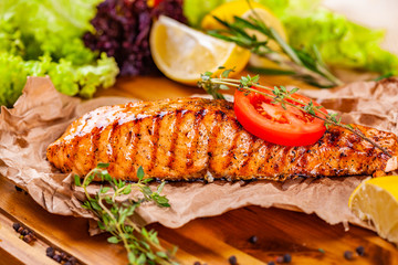 Grilled salmon with tomato and herbs on wooden board