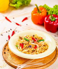 Pasta with seafood and vegetables in white plate on wooden cutting board