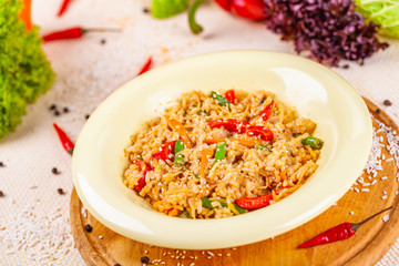 Rice with vegetables in white plate on wooden cutting board