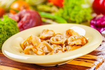 Dumplings with meat in beige plate on wooden board. Russian cuisine