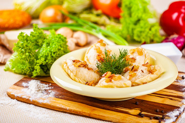 Vareniki with potatoes and mushrooms decorated with fried onion and dill