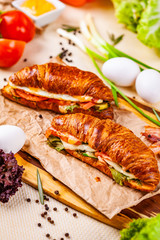 Croissants with bacon, cheese and vegetables on wooden board. Close up
