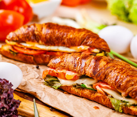 Croissants with bacon, cheese and vegetables on wooden board. Close up