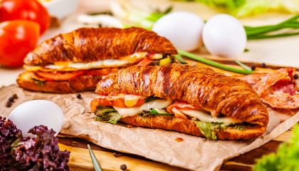 Croissants with bacon, cheese and vegetables on wooden board. Close up