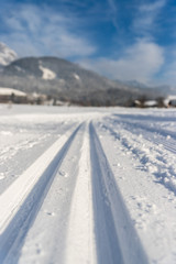 Fototapeta na wymiar Cross-country skiing in Austria: Slope, fresh white powder snow and mountains, blurry background