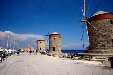 Fototapeta na wymiar The windmills,fort of St Nikolas,Church of the Assumption and the Governors palace are on Rhodes Mandraki Harbour 