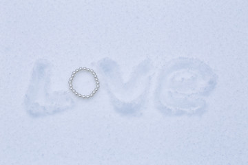 the word love in the snow with a pearl bracelet