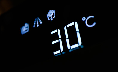 Washing machine panel display, setting 30 degrees temperature. Abstract cold water laundry programming backdrop, closeup.
