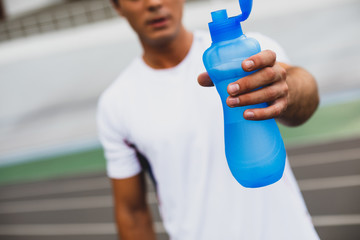 Serene male holding bottle of water outside