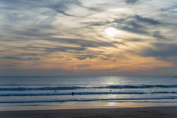 Carcavelos beach filled with many surfers at Sunset, Lisbon, Portugal