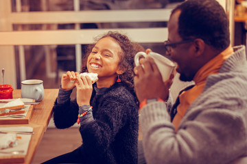 Curly daughter feeling truly satisfied after trying her sandwich