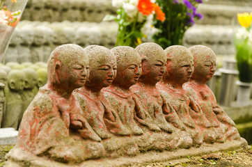 Row of stone statue of monks zen meditating and praying in the asian temple garden