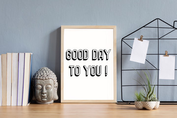 Home office interior with mock up photo frame on the brown wooden table with  accessories, books, air plant in design pots, buddha figure and notes. Grey walls. Minimal concept of mockup.