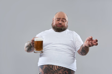 Funny fat man looking drunk while standing with beer