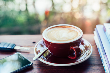 Cup of hot coffee , books , smartphone and keys on the wood plate
