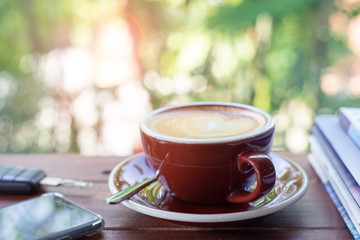 Cup of hot coffee , books , smartphone and keys on the wood plate