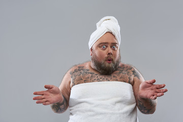 Surprised man in towel putting hands aside and looking funny