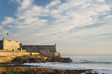Fototapeta na wymiar View of Saint Julian Fortress with lighthouse tower from praia de Carcavelos, Portugal