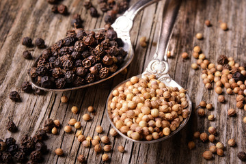 Aromatic spices – black and white peppers on wooden table