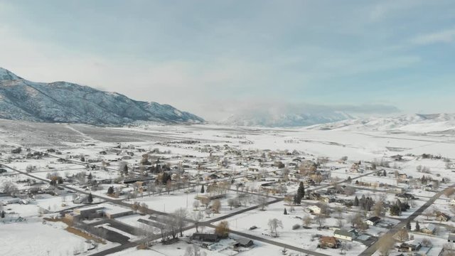 Aerial-Flying high over small rural mountain valley town with snow on the ground