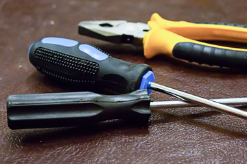 crossed long iron screwdriver yellow pliers close-up industrial design background