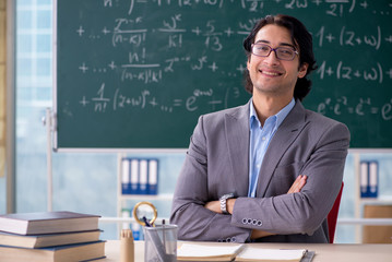 Young handsome math teacher in classroom 