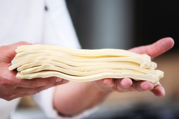 Pastry chef showing dough sheets ready to be rolled to produce croissant .