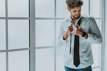 Confident gentleman wearing his tie on shirt