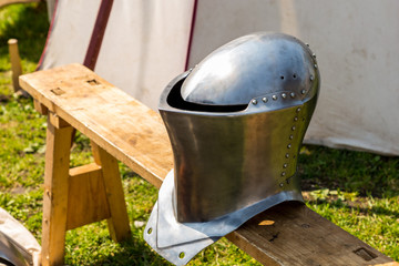 helmet iron shining medieval warrior defense army forged rivets on the background of a marching tent