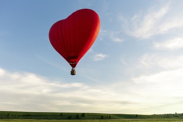 Valentine's Day. Red hot air balloon in the shape of a heart fly in sky. Love, honeymoon and romantic travel concept