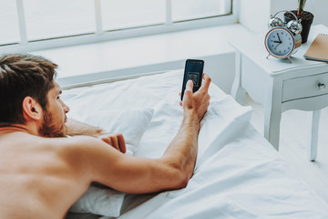 Relaxed guy checking mobile phone in morning