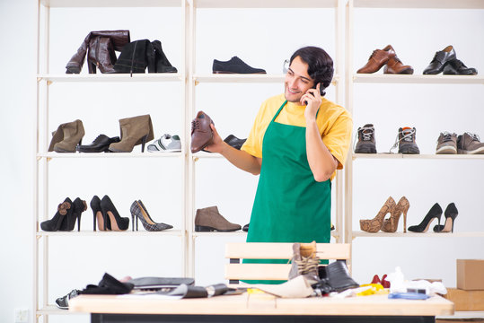 Young man repairing shoes in workshop 