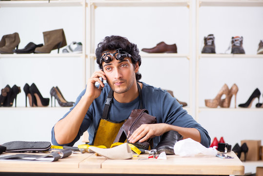 Young man repairing shoes in workshop 