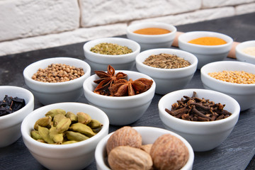 Various spices in bowls on a black slate board. Spices background