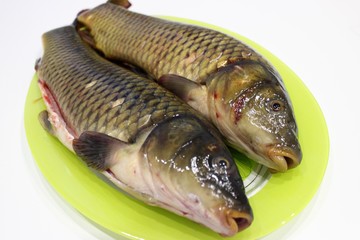  Cleaned carps on a light green dish, which lies on a white table close-up