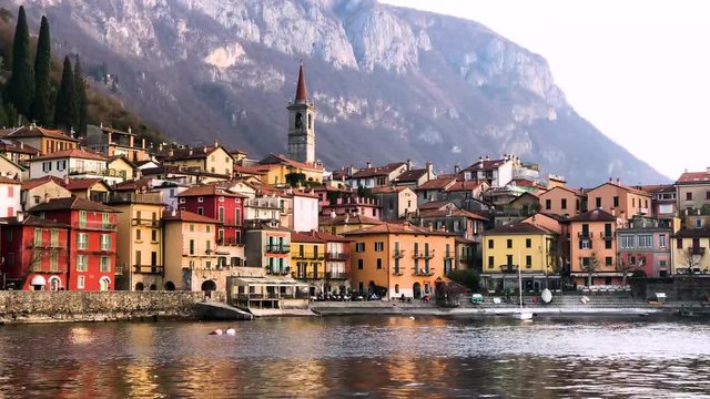 View from a boat of the shores of Lake Como with the town of Varenna and the Italian Alps in background, 4k footage video.