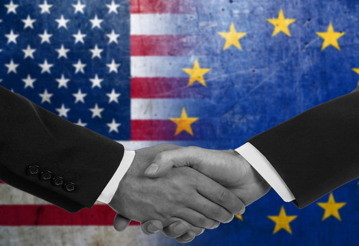 Two men/politicians in suits shaking hands with the national flags on the background - USA and EU