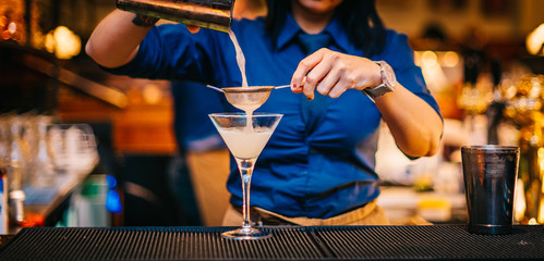 Female bartender preparing making serving alcoholic drink cocktail on bar counter top